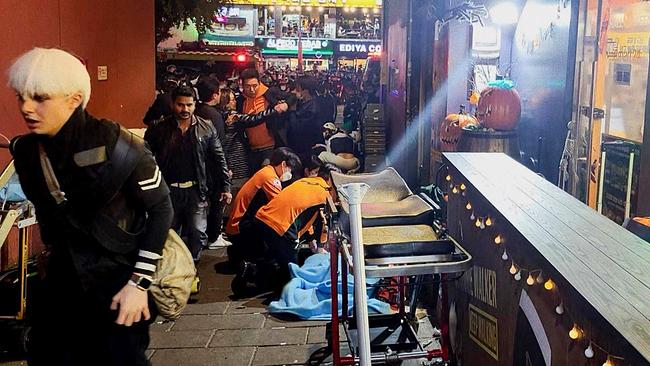 Zwei Rettungskräfte behandeln eine vor einem Lokal am Boden liegende Person, eine Rettungsliege steht bereit