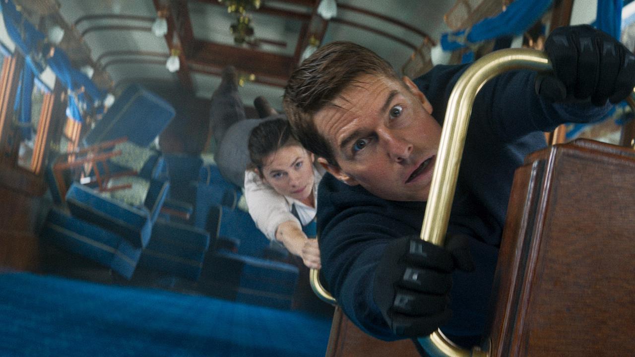 © ORF/PRO7/Paramount Pictures Tom Cruise als Ethan Hunt und Hayley Atwell als Grace halten sich in einem stark schräg liegenden Zugabteil an Metallstangen fest, lose Gegenstände fliegen umher
