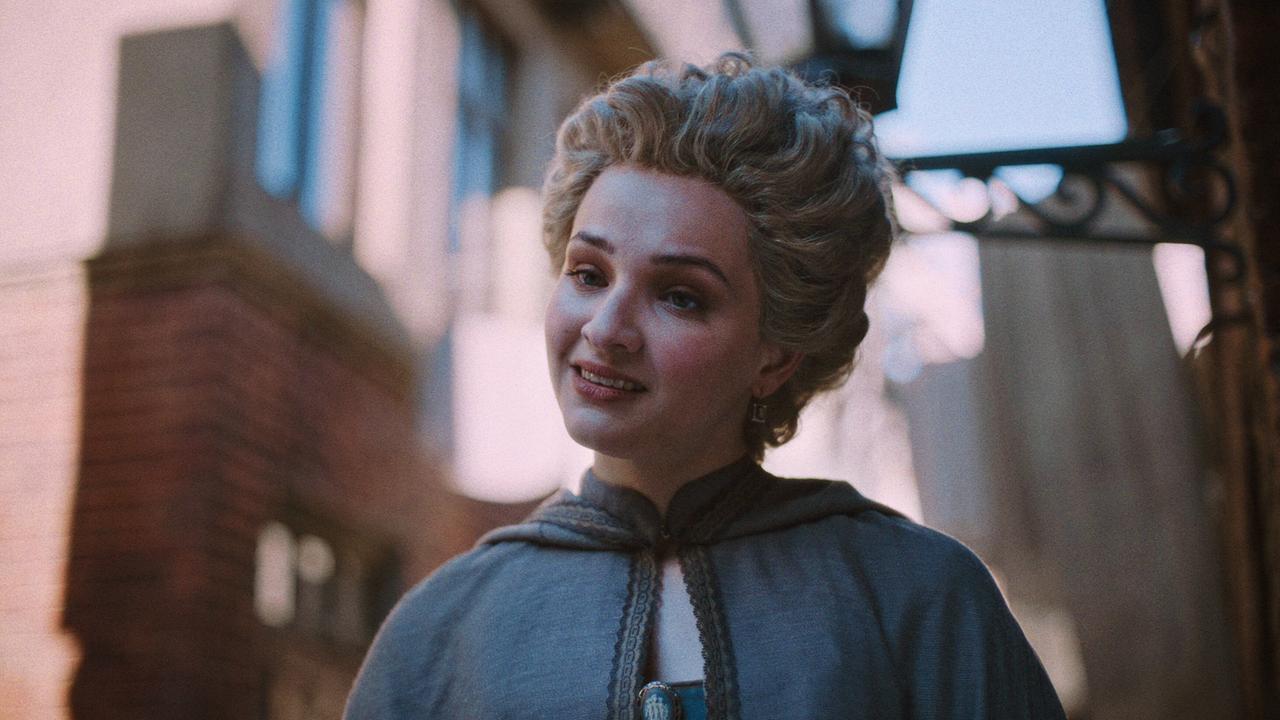 Lisa Vicari als Gräfin von Greiner mit weißer Perücke mit grauem Mantel vor der sonnenbeleuchteten Fassade eines herrschaftlichen Hauses