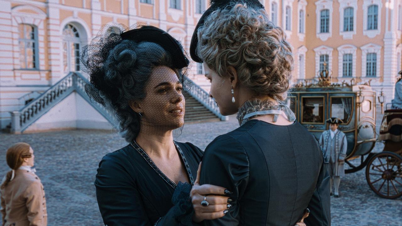 © ORF/WDR/Story House Pictures/Armands Virbulis Marie Antoinette schaut Gräfin von Greiner in die Augen und hält sie fest, hinter den beiden steht eine Kutsche abfahrtsbereit im Schlosshof