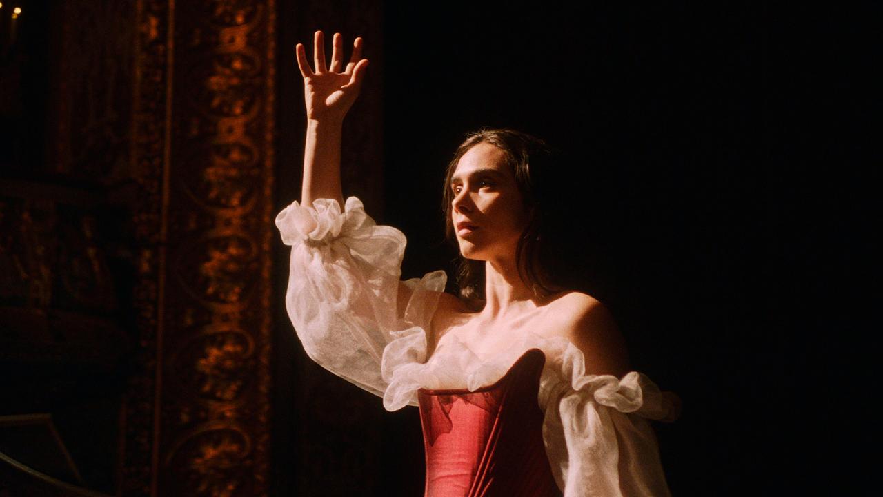 © ORF/WDR/Story House Pictures Maria Anna Mozart steht in dramatischer Pose im roten Kleid mit durchsichtigen, weißen Ärmeln auf der Bühne