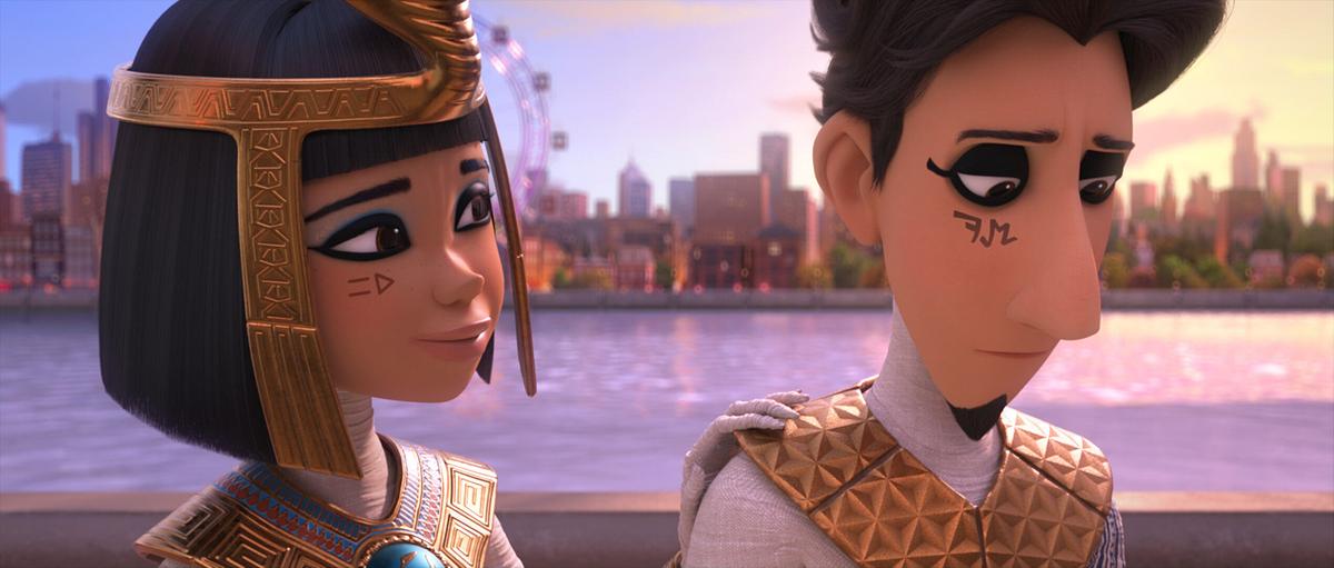 © ORF/Warner Bros. Pictures Eine junge Frau blickt aufmunternd zu einem jungen Mann, der betrübt zum Boden schaut, beide sind in weißer, altägyptischer Kleidung gekleidet, hinter ihnen ein Gewässer und die Skyline einer modernen Großstadt