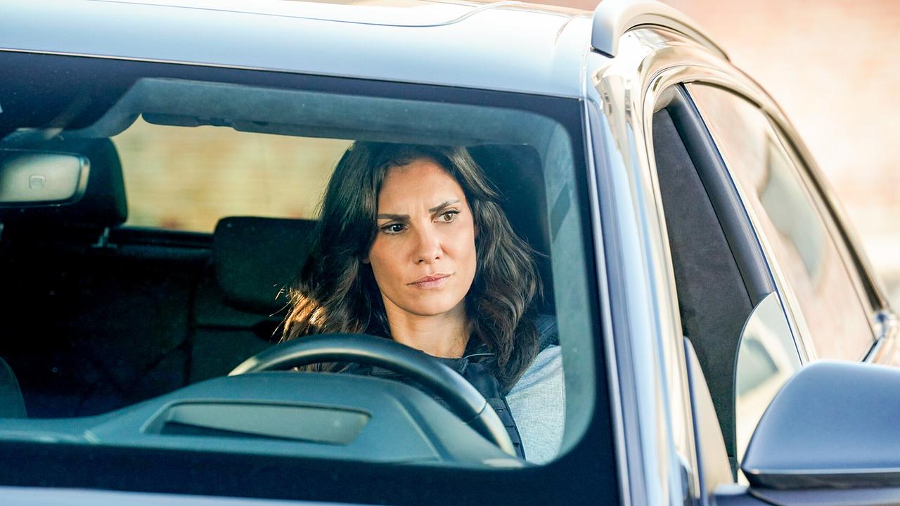 © ORF/Sevenone International/CBS/Robert Voets Kensi sitzt am Steuer ihres stehenden Wagens, und blickt nachdenklich zur Seite