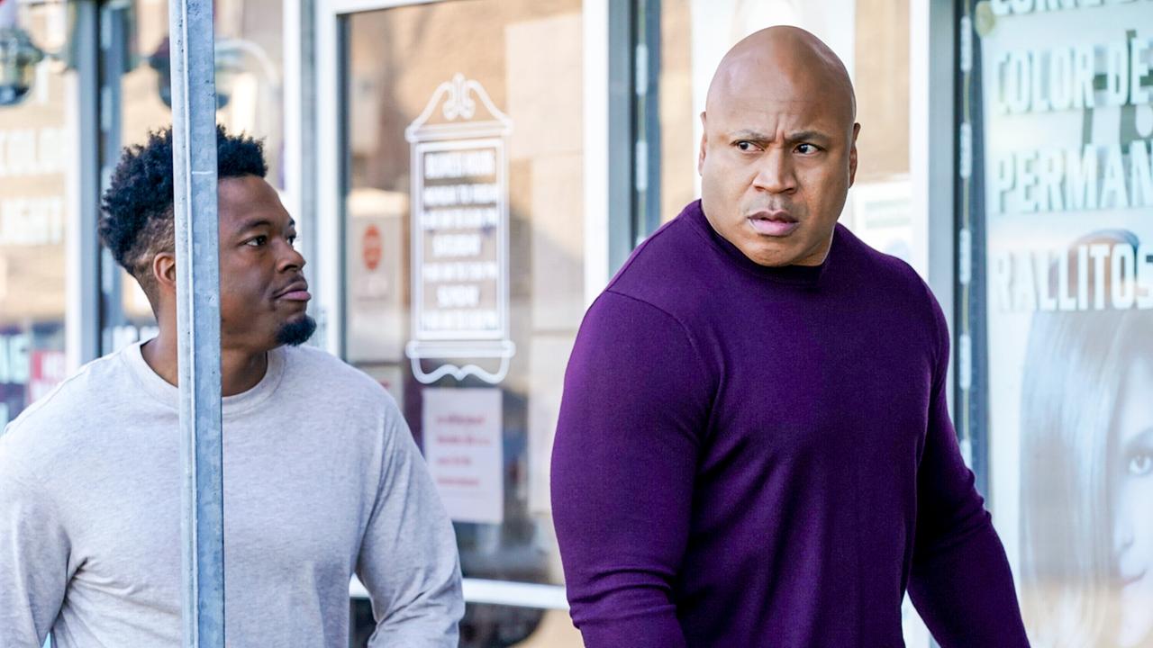 © ORF/Sevenone International/CBS/Michael Yarish Zwei Männer, einer in hellgrauem Oberteil und der andere in dunkelviolettem Langarmshirt, gehen nebeneinander vor Glastüren und Schaufenstern eines Geschäfts