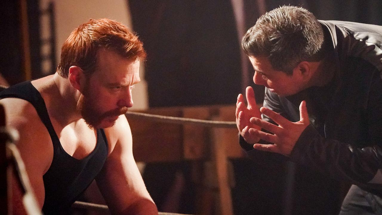 © ORF/Sevenone International/CBS/Michael Yarish Ein rothaariger, bärtiger Boxer sitzt in der Ecke des Boxrings, ein Mann in schwarzer Lederjacke redet auf ihn ein