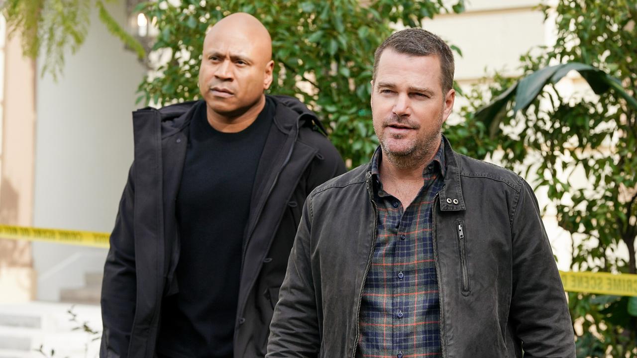 © ORF/Sevenone International/CBS/Michael Yarish Zwei Männer in schwarzen Jacken stehen vor dem Vorgarten eines Gebäudes, hinter ihnen ist das Absperrungsband eines Tatorts zu sehen