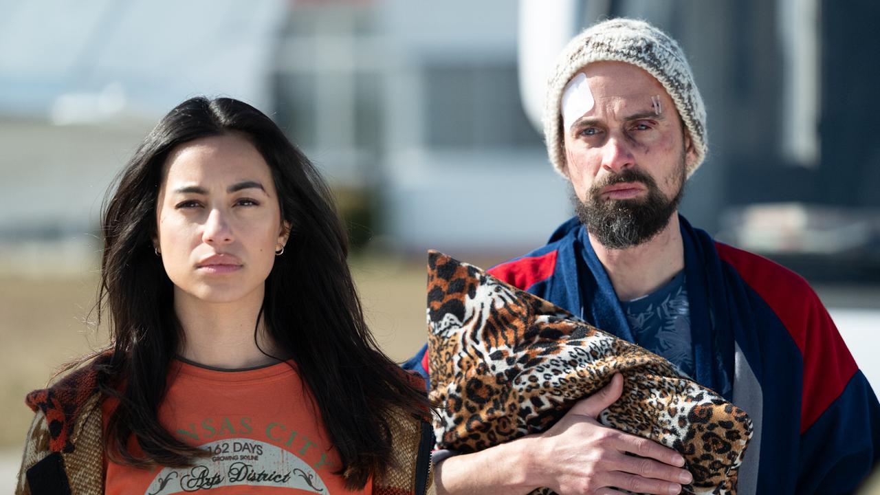 Die ernst blickende Samira Leoni steht im Freien neben dem verletzten Jan Miracek mit Mütze, der einen Leoparden-Polster in der Hand hält.