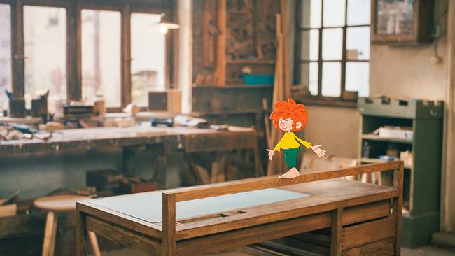 Pumuckl spaziert durch die Tischlerwerkstatt.