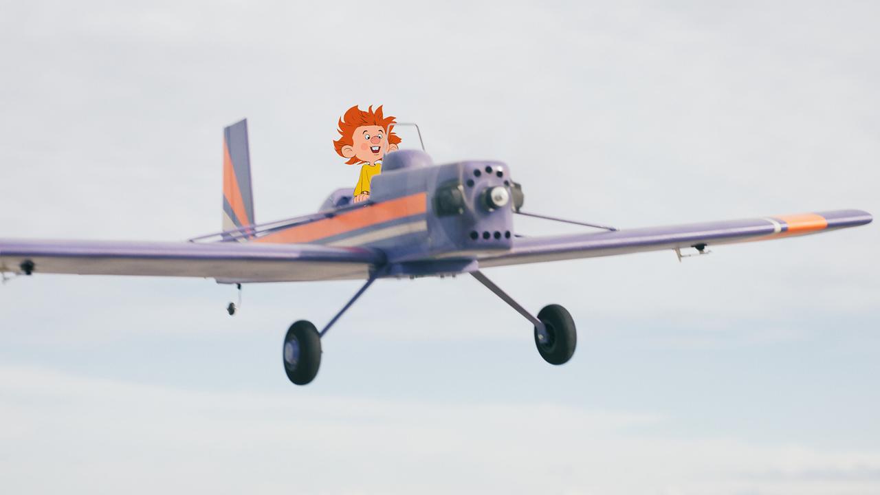 Pumuckl hoch in der Luft am Steuer eines Flugzeugs.