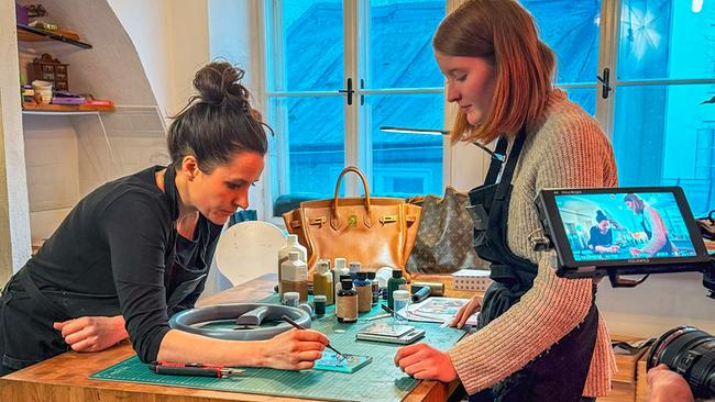 Christina Roth an ihrem Arbeitstisch mit ihrem Lehrling Carolina in der Lederwerkstatt in der Salzburger Innenstadt.