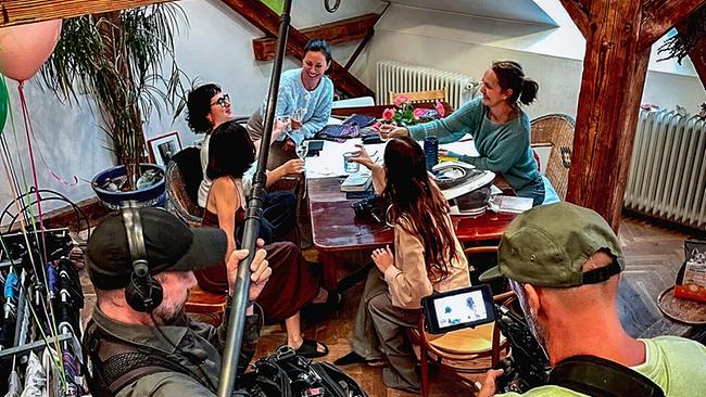 © ORF/DMG Film Astrid Lindbergh bei der Besprechung vor dem Fotoshooting mit ihren Freundinnen an einem Tisch in einer rustikalen Dachwohnung in Wien.