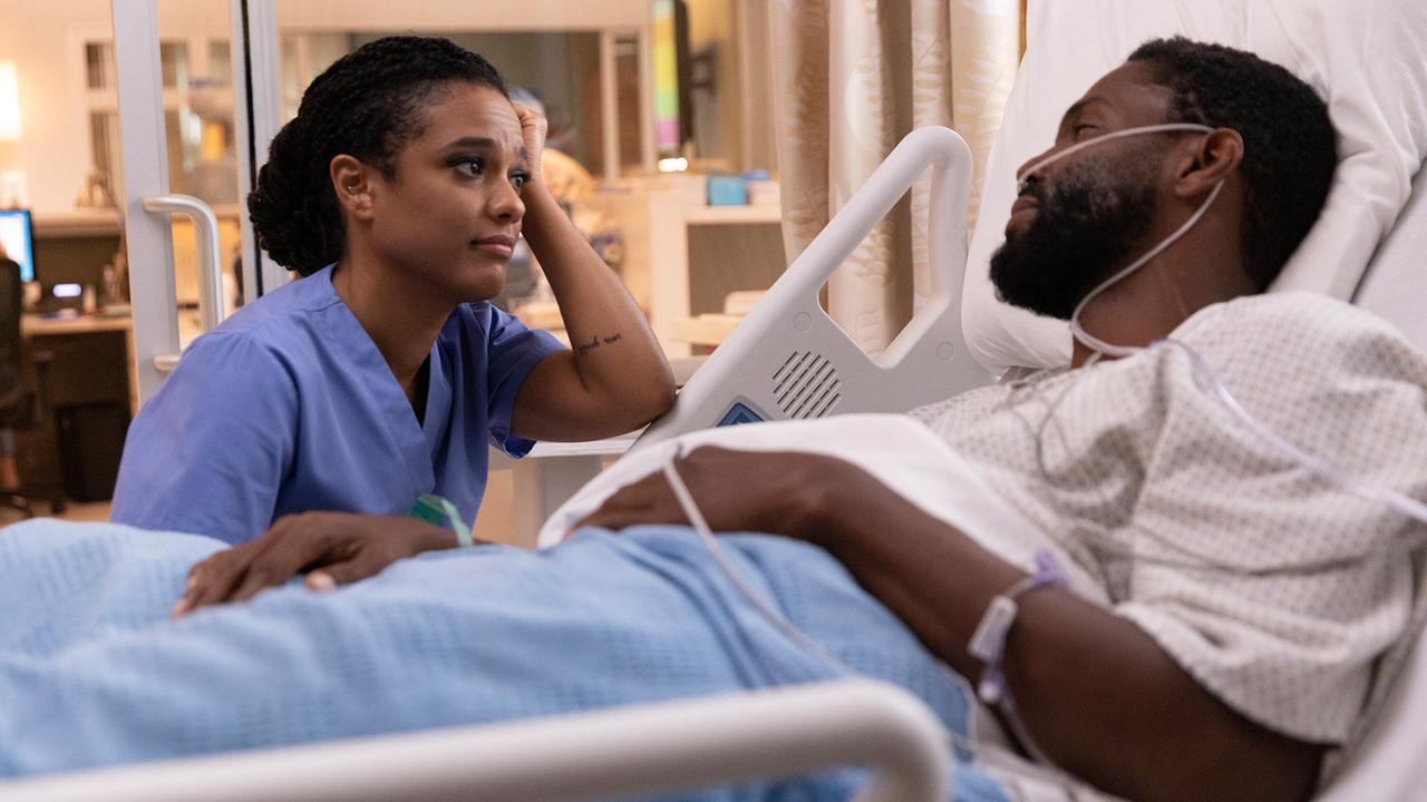 Eine Krankenpflegerin sitzt am Bett eines Patienten und sieht ihm während des Gesprächs tief in die Augen