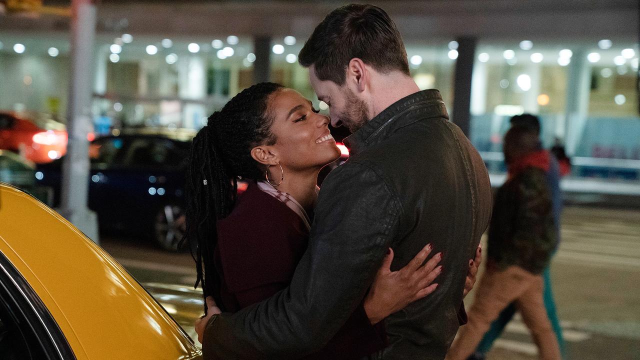 © ORF/Universal/NBC/Virginia Sherwood Eine Frau und ein Mann umarmen sich sich innig vor einem gelben Taxi bei Nacht, im Hintergrund sind unscharf Lichter und Passanten zu sehen