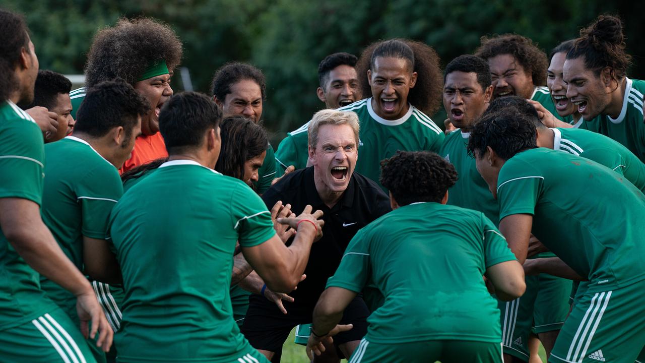 Michael Fassbender als Trainer Thomas Rongen, umgeben von Fußballspielern feuert er sein Team an