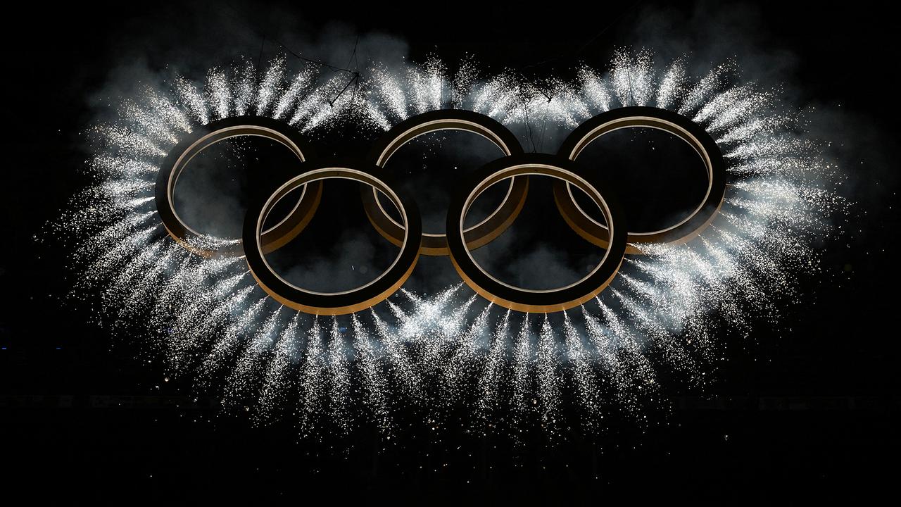 Die von Feuerwerk umgebenen Olympischen Ringe vor dunklem Hintergrund während der Eröffnungsfeier der Olympischen Winterspiele Milano Cortina 2026 im San-Siro-Stadion in Mailand