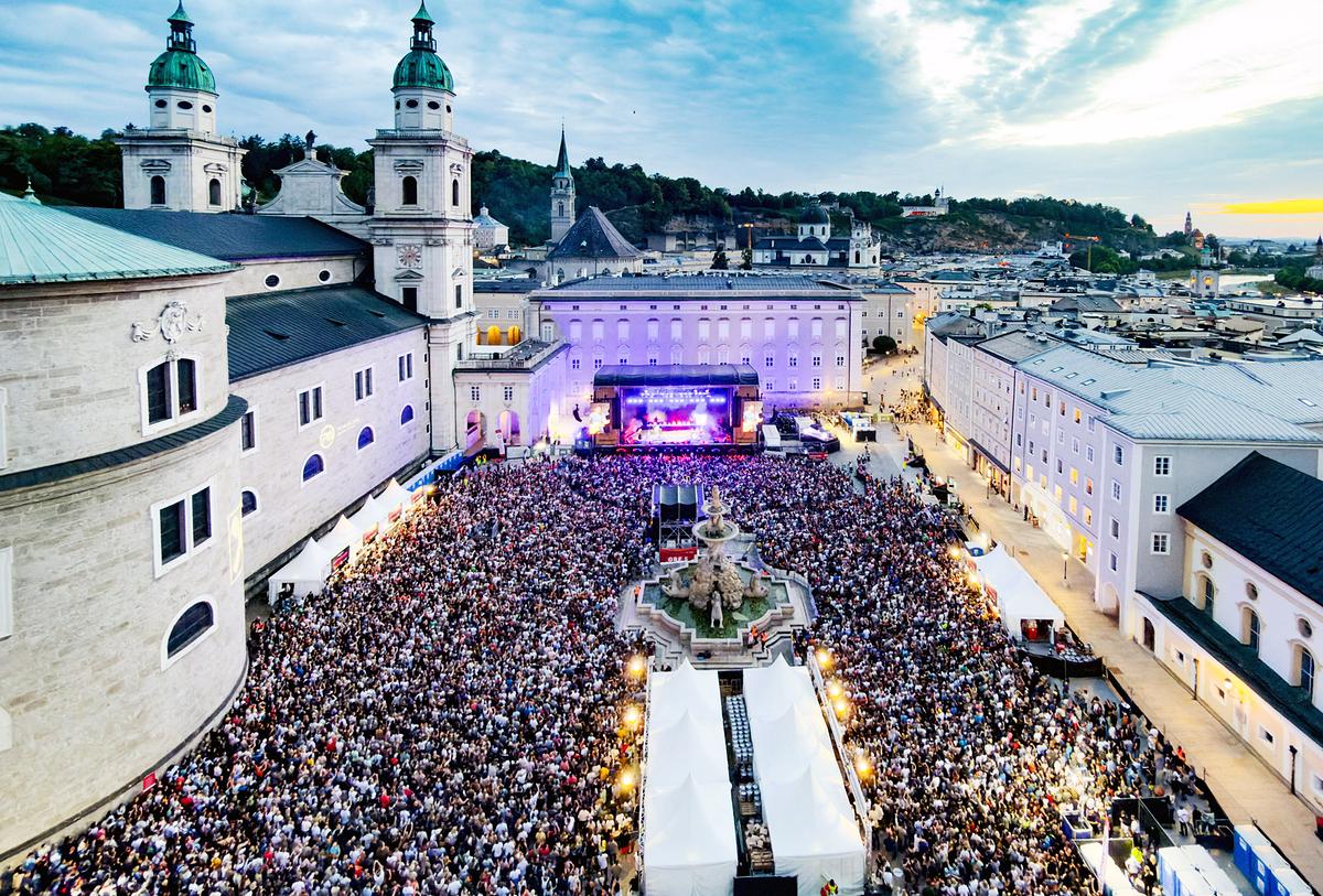 © ORF/Landesstudio Salzburg/wildbild Tausende Menschen feiern bei einem Open-Air-Konzert auf dem Salzburger Residenzplatz vor der historischen Altstadtkulisse.