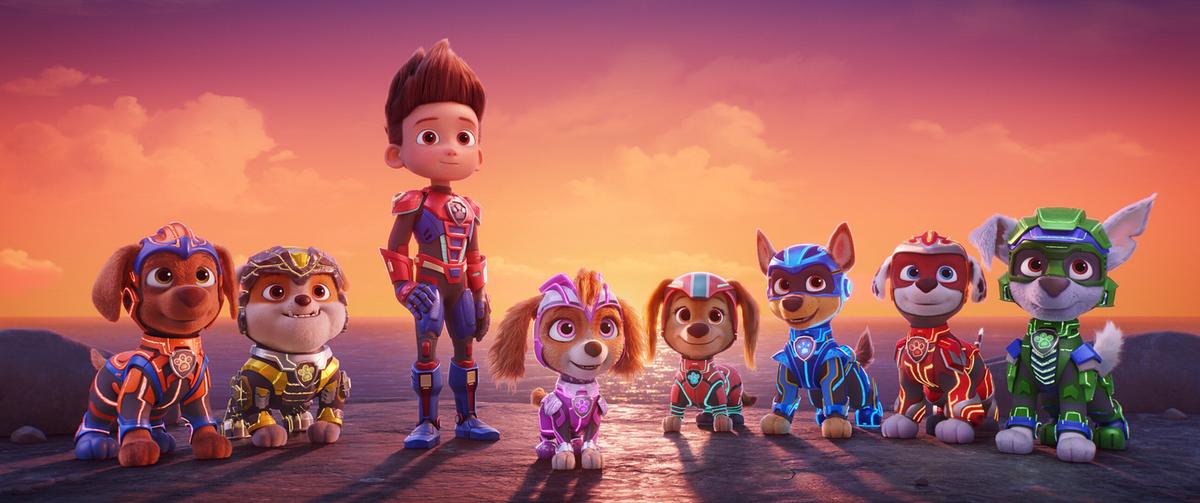 Ein Bub und die sieben Welpen der Paw Patrol - stehen in ihren Schutzmonturen vor einem orangefarbenen Abendhimmel
