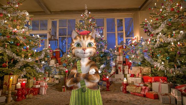 Der Findus Kater blickt mit roter Haube am Kopf in die Kamera - zwischen drei weihnachtlich geschmückten Christbäumen türmen sich hinter ihm verpackte Geschenke