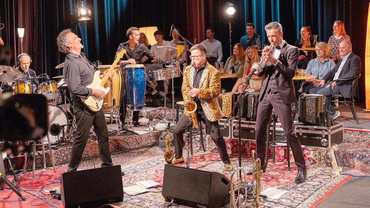 © ORF/Landesstudio Salzburg/Georg Hummer Herbert Pixner und die Italo Connection spielen vor Publikum in einem gemütlich beleuchteten Studio mit Schlagzeug, Gitarre, Saxofon und Trompete bei "Pixner’s Jam Session 2026".
