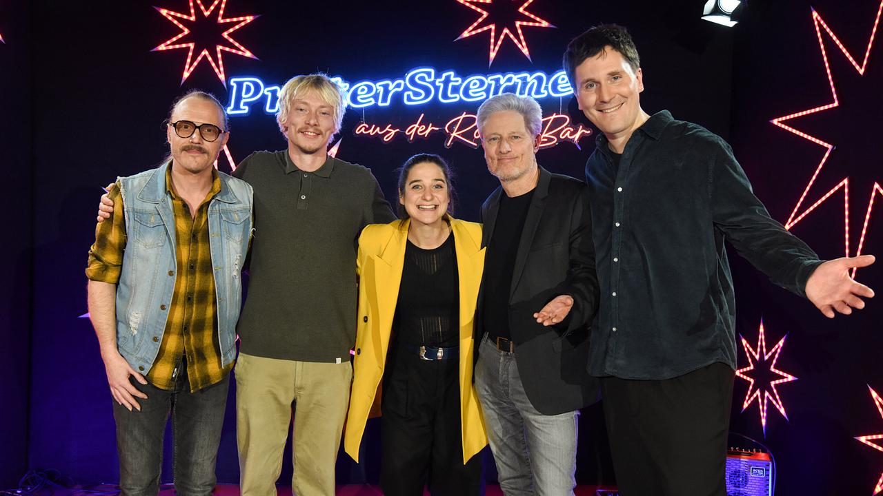  Christoph Jarmer, Robert Alan, Christina Kiesler, Florian Scheuba und Hosea Ratschiller stehen auf der Bühne mit leuchtenden Sternen und Neon-Schriftzug "Pratersterne - Rote Bar".