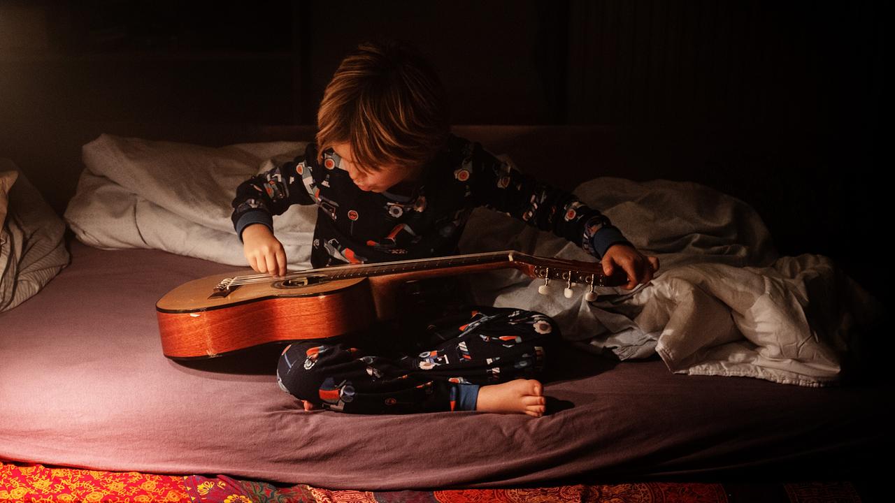 "Rickerl – Musik is höchstens a Hobby": Dominik (Ben Winkler) sitzt am Bett und spielt mit seiner Gitarre.