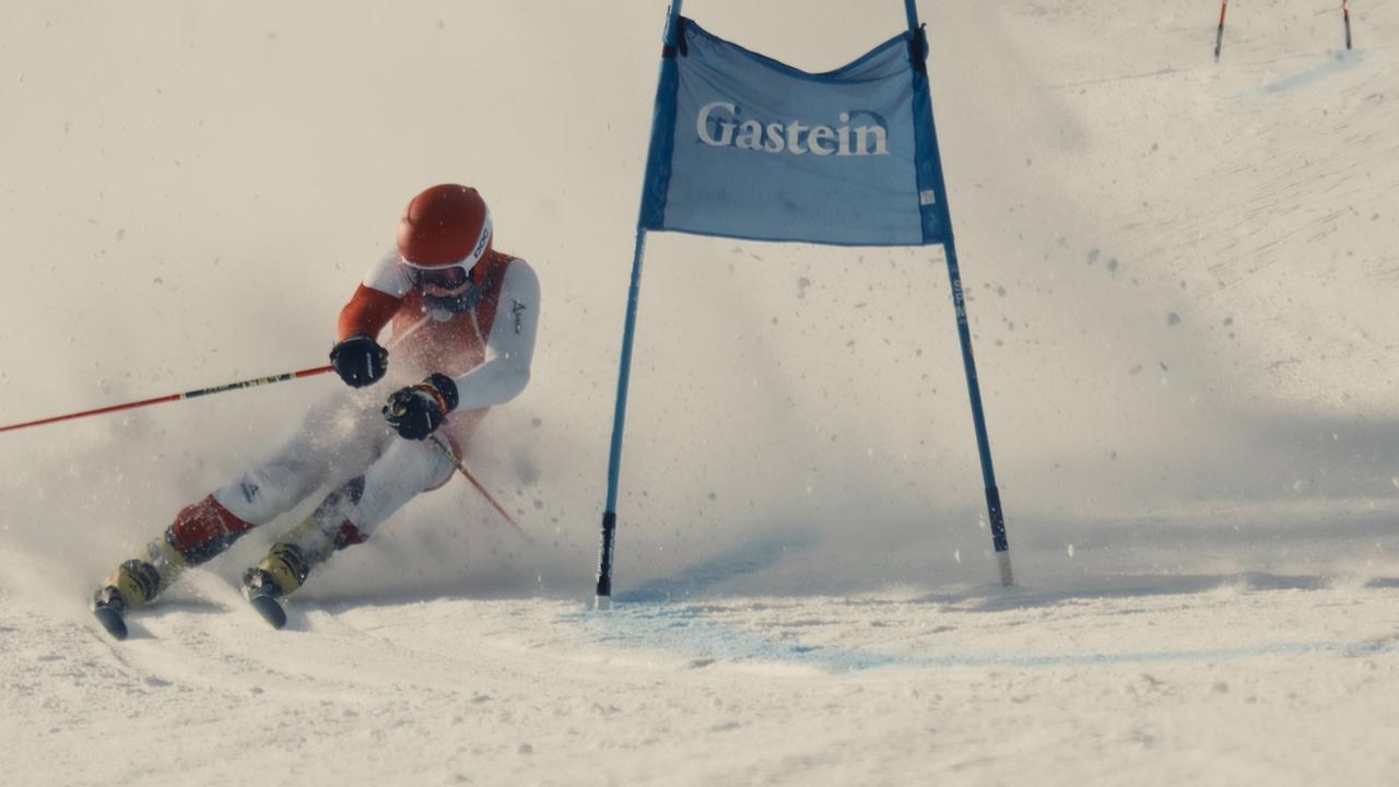 Ein Skirennläufer fährt mit hoher Geschwindigkeit auf einer Piste an einem Tor im Schnee vorbei.