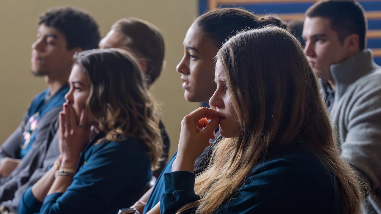 Solenn Eden, Nawal Ammann, Dani Strobl und Georg Stoiber sitzen in einer Turnhalle und blicken ernst nach vorne.