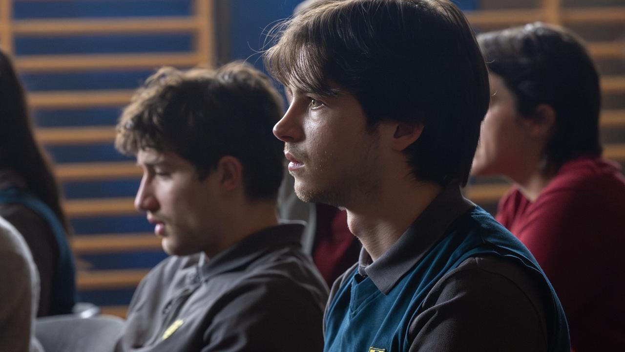 Nikki Auer, Luca Rossi und Tina sitzen in einem Turnsaal nebeneinander und blicken konzentriert nach vorne.