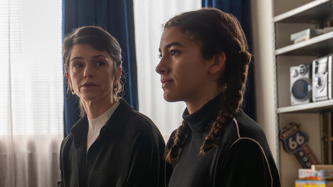 Sofia Ammann und Nawal Ammann sitzen nebeneinander an einem Tisch in einem Raum und hören jemandem zu.