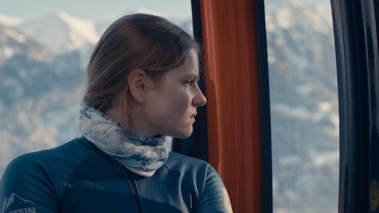 Dani Strobl sitzt in einer Gondel und blickt auf die verschneiten Berge draußen.