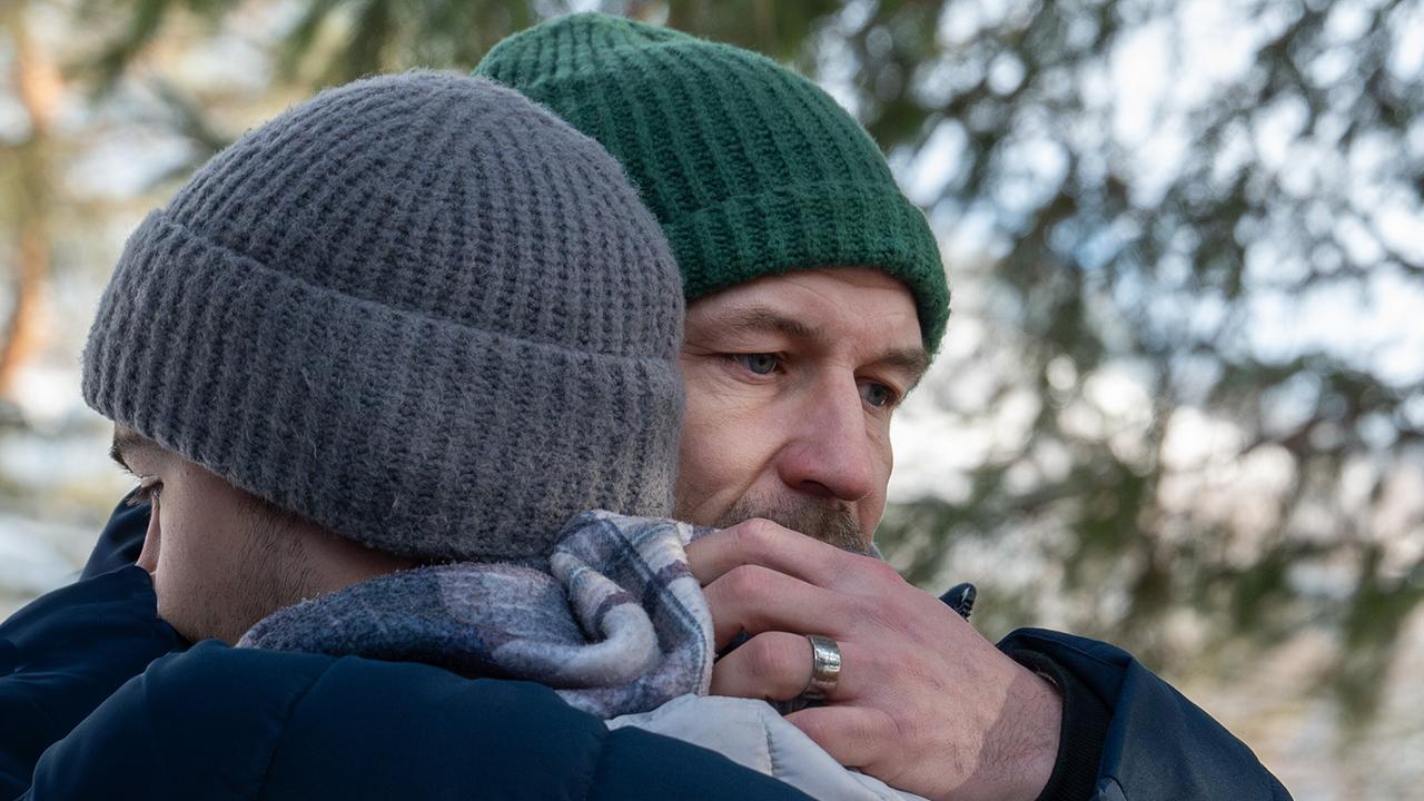 Mario Rossi umarmt seinen Sohn Luca im Freien an einem winterlichen Tag.
