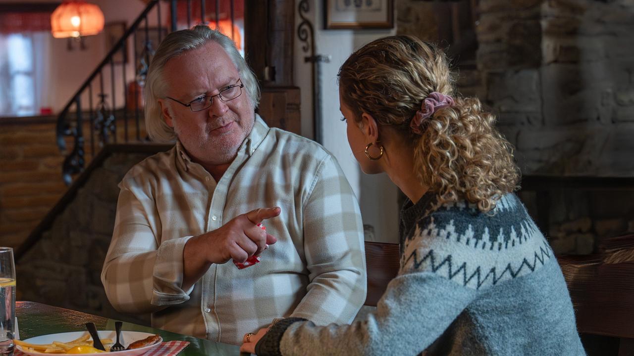 Schiesstl und Steffi Strobl sitzen in einem gemütlichen Gasthaus und führen ein Gespräch bei einem gedeckten Tisch.