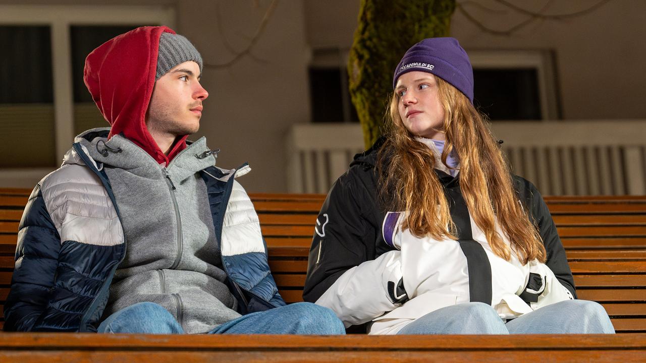 Luca Rossi und Dani Strobl sitzen in Winterkleidung auf einer Parkbank.