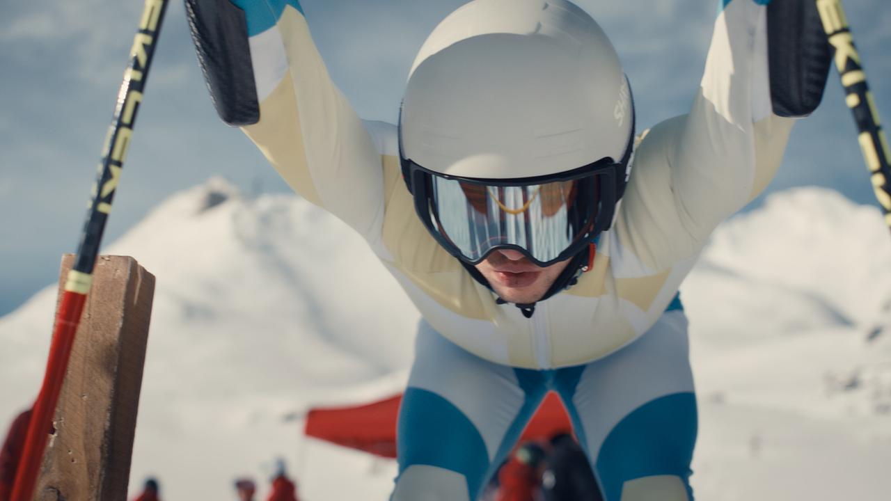 Skirennläufer Nikki Auer beugt sich im Startgate kraftvoll nach vorne, bereit zum Rennstart.