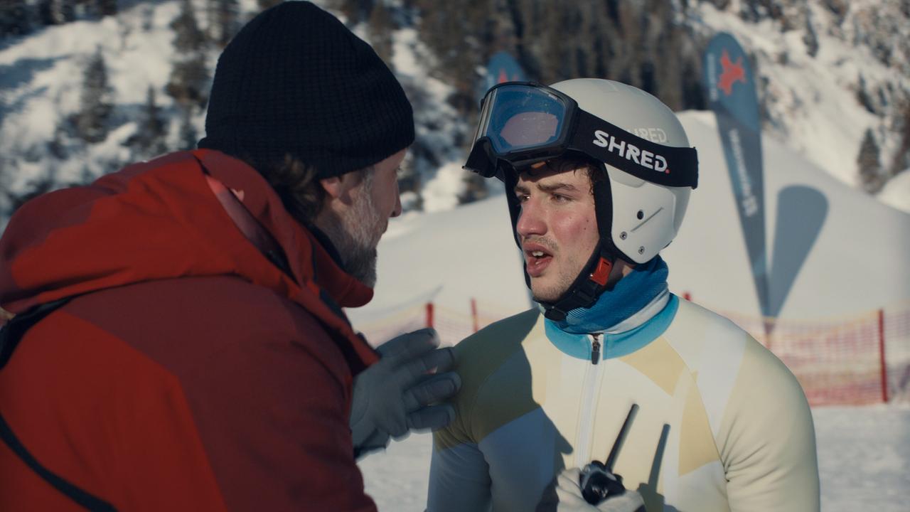Christian im Gespräch mit dem Skirennläufer Nikki Auer  vor einer verschneiten Piste.