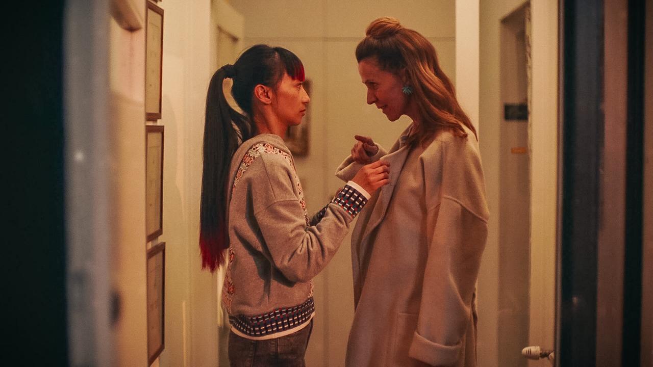 Saya spricht in einem schmalen Flur mit Valeria, die gerade ihren Mantel anzieht.