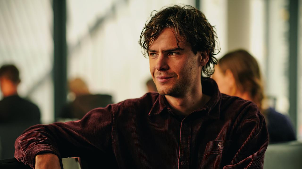 Fabian Polly sitzt lächelnd im Flughafengate.