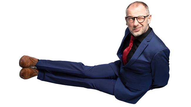 © ORF/Dominic Reichenbach Severin Gröbner im blauen Anzug und mit roter Krawatte liegt vor weißem Hintergrund quer im Bild und zwinkert in die Kamera.