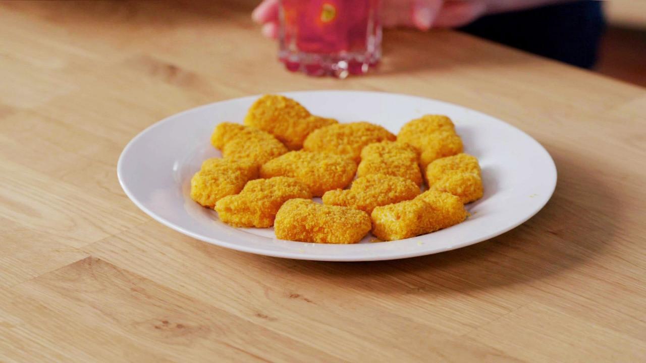 Zubereitete Supermarkt-Chicken Nuggets  auf einem weißen Teller auf einem Holztisch