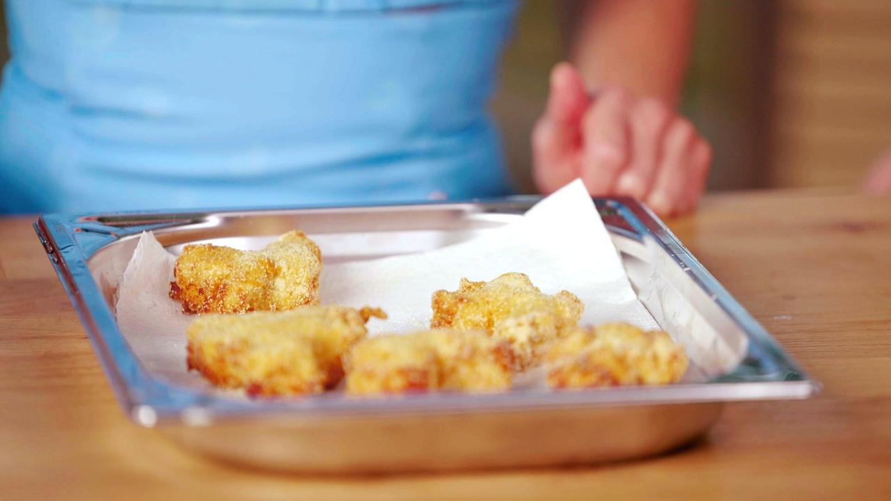 Mehrere selbst gemacht Chicken Nuggets auf einem Backblech mit Papier