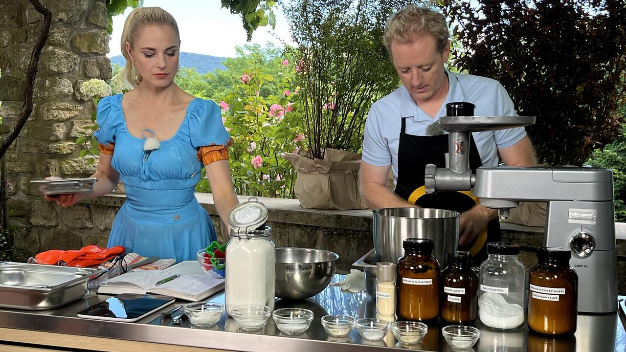 Silvia Schneider und Fritz Treiber stehen an einer Outdoorküche mit Küchenmaschine, Schüsseln und Gläsern