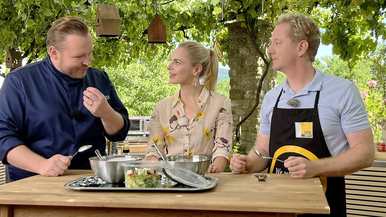 Richard Rauch, Silvia Schneider und Fritz Treiber stehen an einem Holztisch im Freien, vor ihnen ein angerichteter Salat