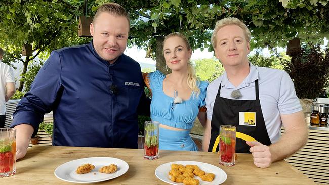 © ORF/On Media Richard Rauch, Silvia Schneider und Dr. Fritz Treiber stehen an einem Holztisch im Freien und kosten Chicken Nuggets