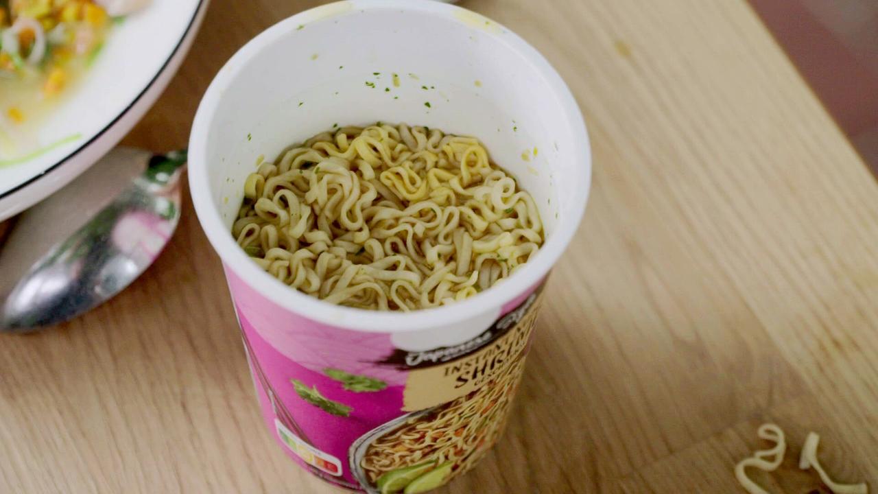 Ein geöffneter Cup Instantnudeln auf einem Holztisch