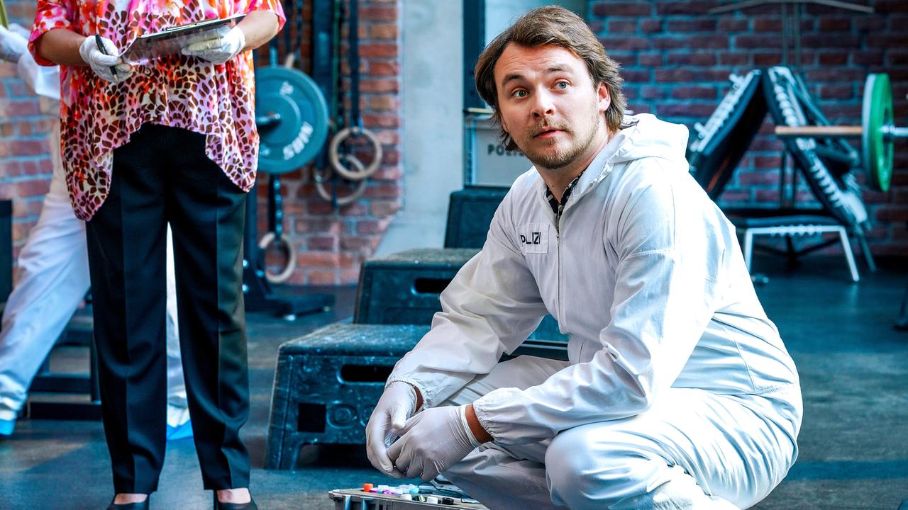 Julius Rubatsch in Schutzkleidung hockerlt im Fitnessstudio neben seiner Ausrüstung und blickt nach vorne.