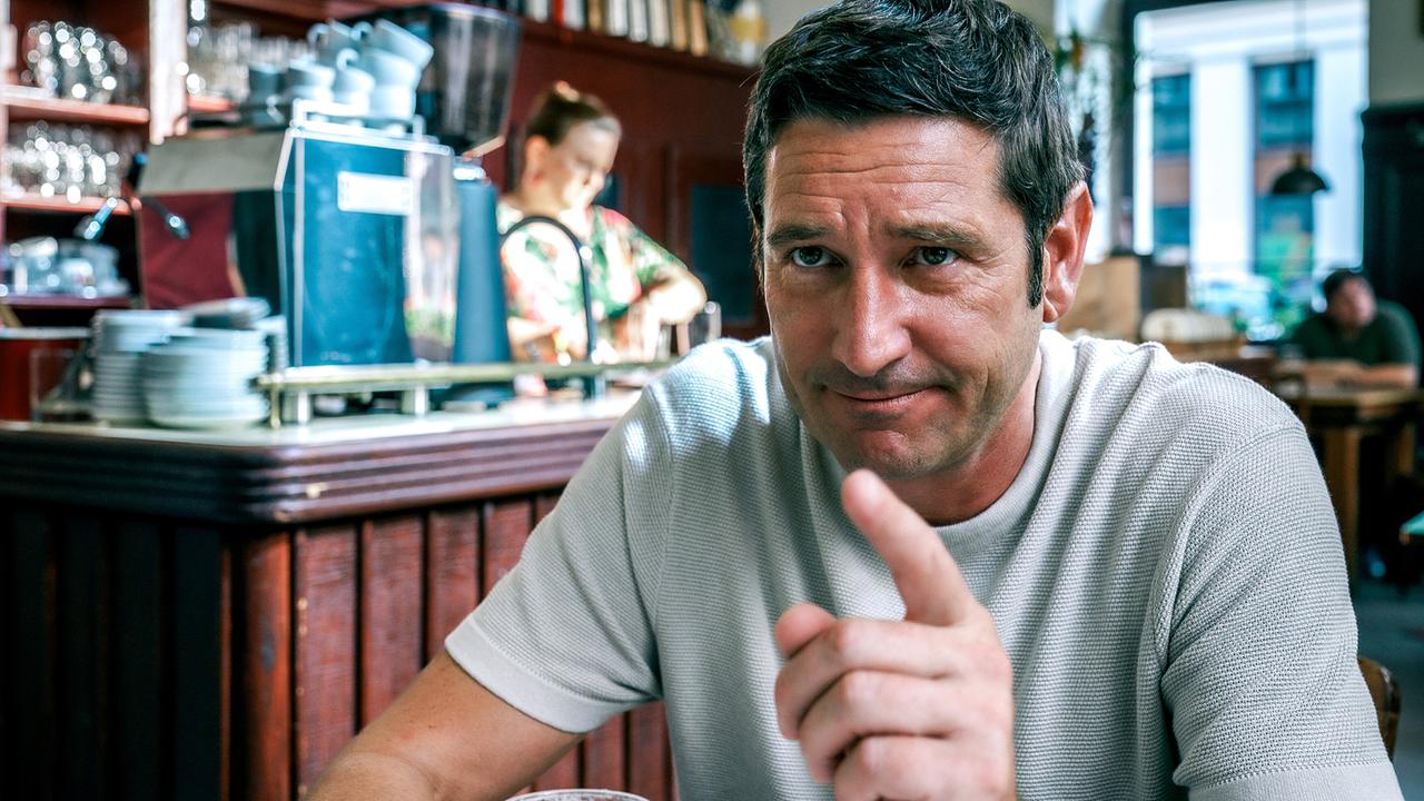 Klaus Lechner sitzt im Wirtshaus vor einem Glas Bier und hebt erklärend den Zeigefinger.