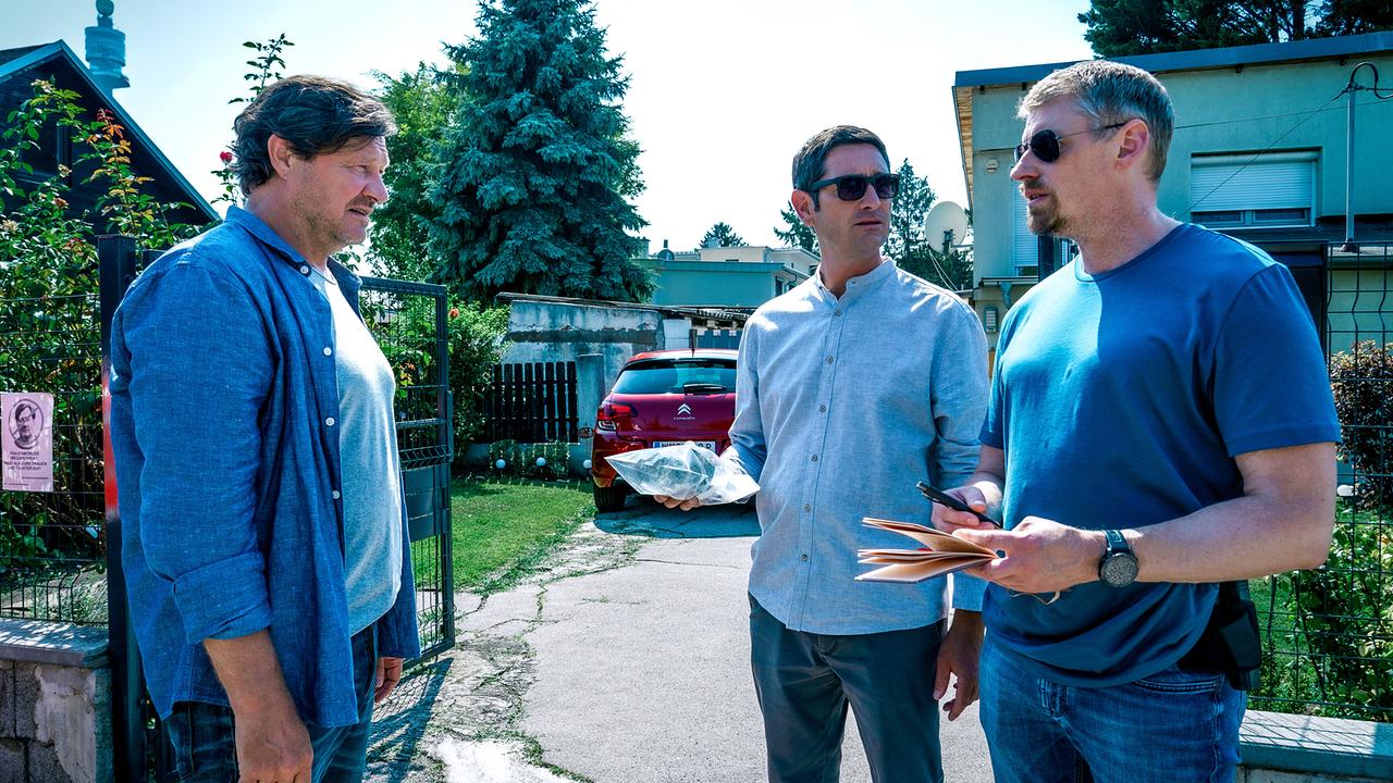© ORF/Satel Film/Petro Domenigg Gernot Polmer, Klaus Lechner und Max Herzog unterhalten sich vor einem Gartentor in einer ruhigen Wohngegend.