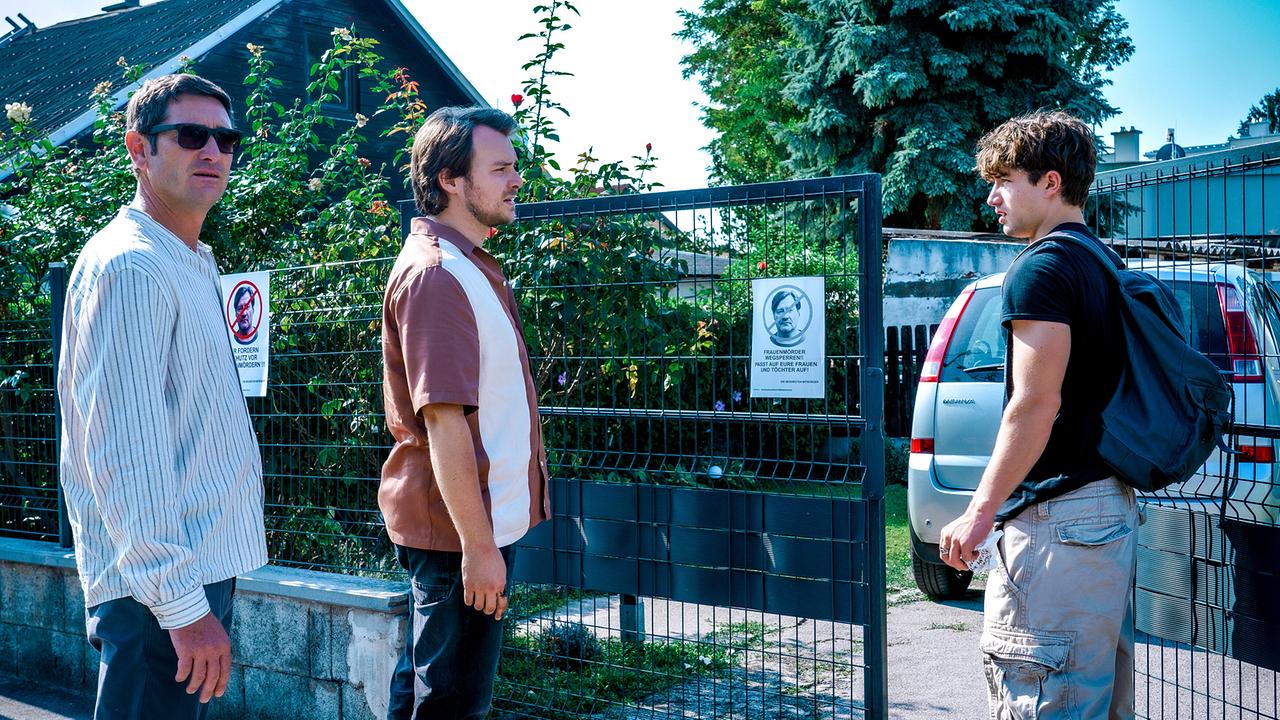 © ORF/Satel Film/Petro Domenigg Klaus Lechner und Julius Rubatsch stehen vor einem Gartentor neben Lukas Polmer mit Rucksack, der gerade das Tor öffnet.