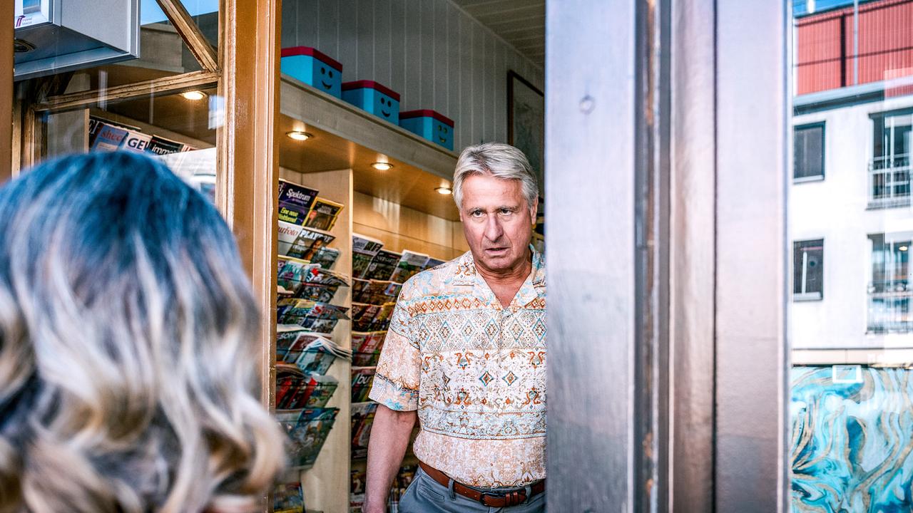 © ORF/Satel Film/Luca Breuer Helmut Brandl steht im Eingang einer Trafik mit Blick nach draußen auf Ingrid Zuber ihm gegenüber, die von hinten zu sehen ist.