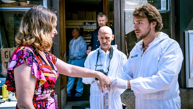 Julius Rubatsch sichert vor der Trafik das Smartphne von  Ingrid Zuber, im Hintergrund stehen weitere Einsatzkräfte und Max Herzog.